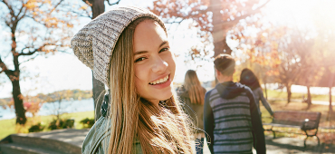 Mädchen mit Mütze lacht mit Freunden im Hintergrund